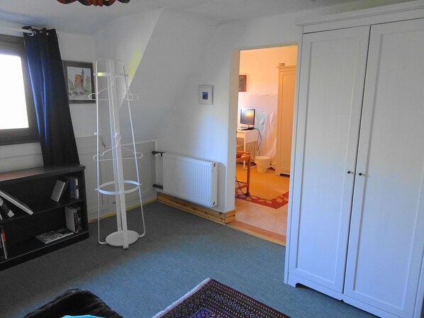 A room with a radiator, a white wardrobe, a bookshelf, and a window with curtains. - Haus Fermate (Wilhelmsfeld)
