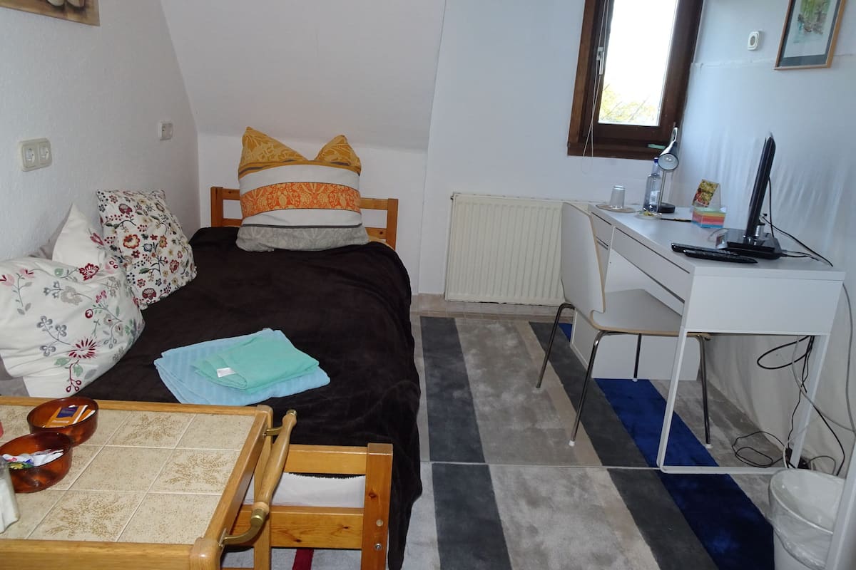 A compact bedroom with a bed, a desk, and a chair.