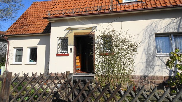 A two-story house with a red-tiled roof, a wooden fence, and a small garden. - Haus Fermate (Wilhelmsfeld)