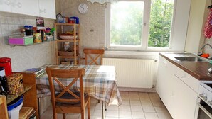 A kitchen with a dining table, chairs, a window, and a radiator. - Haus Fermate (Wilhelmsfeld)