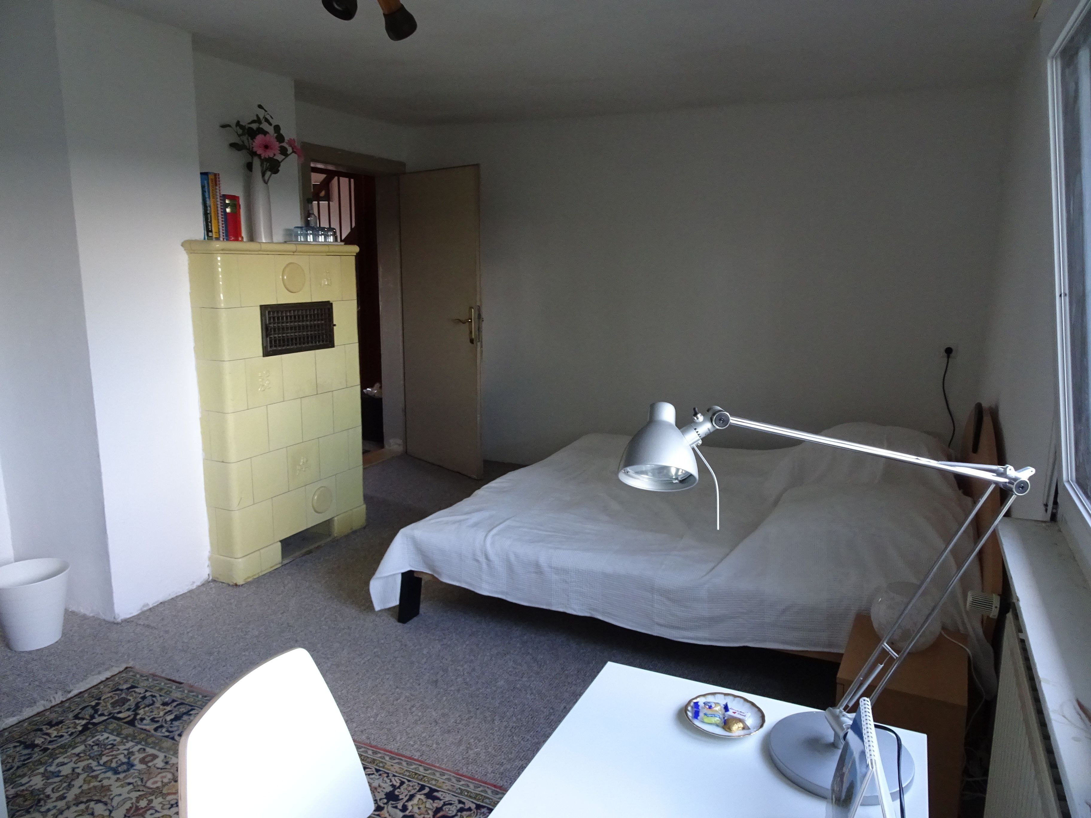 Un dormitorio con cama, escritorio, lámpara, cómoda y ventana.