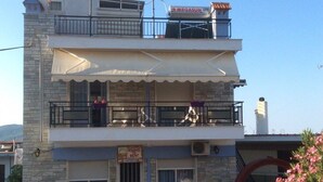 A two-story building with a sign for 'Rooms for Rent' and a 'Megasun' sign on the roof. - Natalie Apartments (Sithonia)