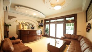 A hotel lobby with a reception desk, leather sofas, a coffee table, and large windows. - JD Hotel Four Boutique (Jaipur)
