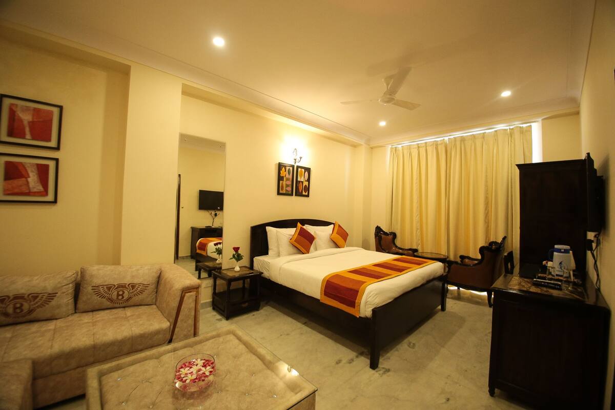 A hotel room with a bed, a sofa, a coffee table, a TV, and a desk.