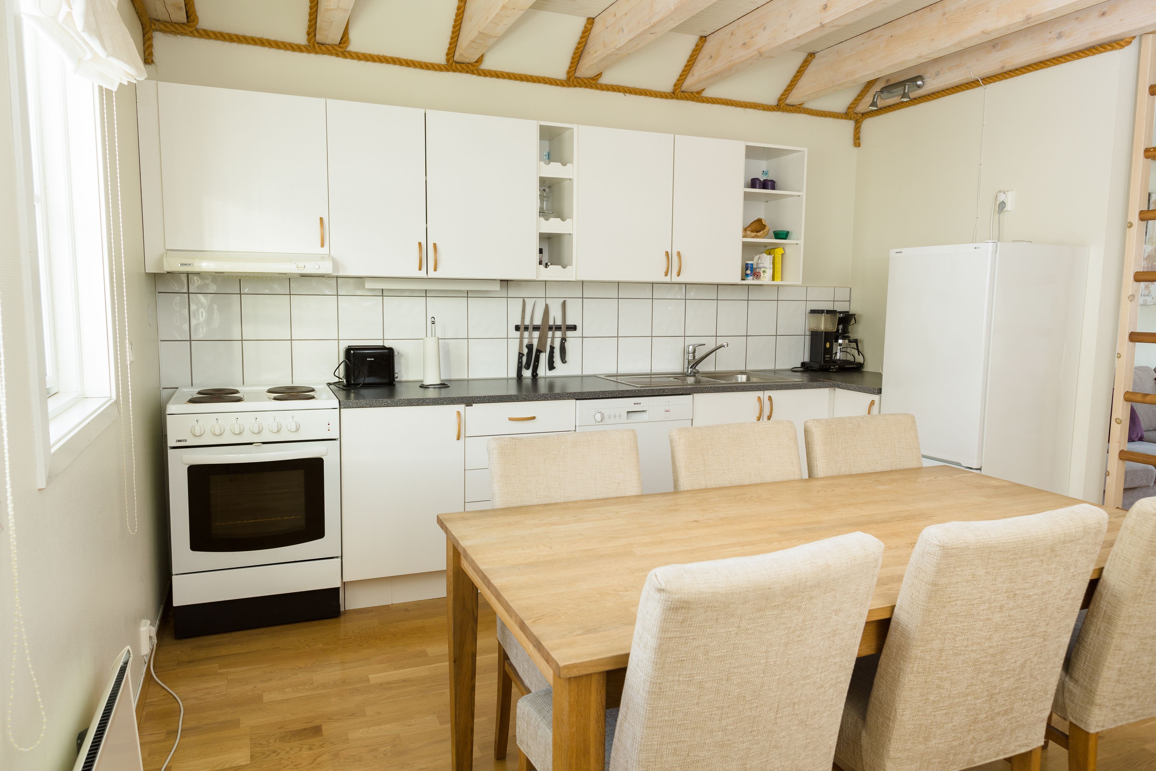 A kitchen with white cabinets, a wooden table, and chairs.