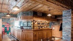 A rustic bar area with wooden counters and stone walls. - Hotel Rozka (Cerklje na Gorenjskem)