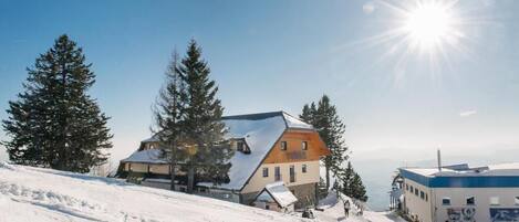 A snow-covered ski resort with a prominent building featuring a sloped roof and a wooden facade.