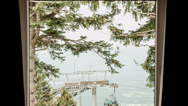 A window with a view of a cable car system, a lamp, and a tree. - Hotel Rozka (Cerklje na Gorenjskem)