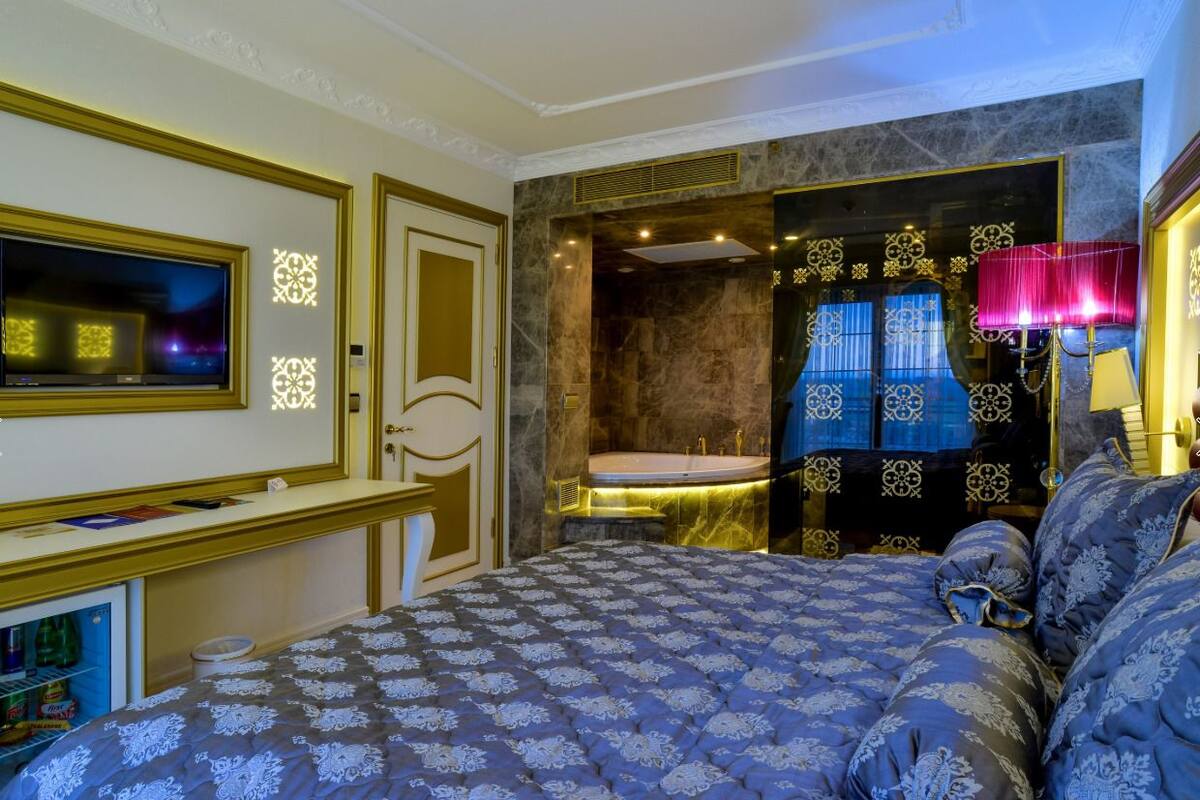 Un dormitorio con una cama grande, televisión, tocador con espejo y bañera.