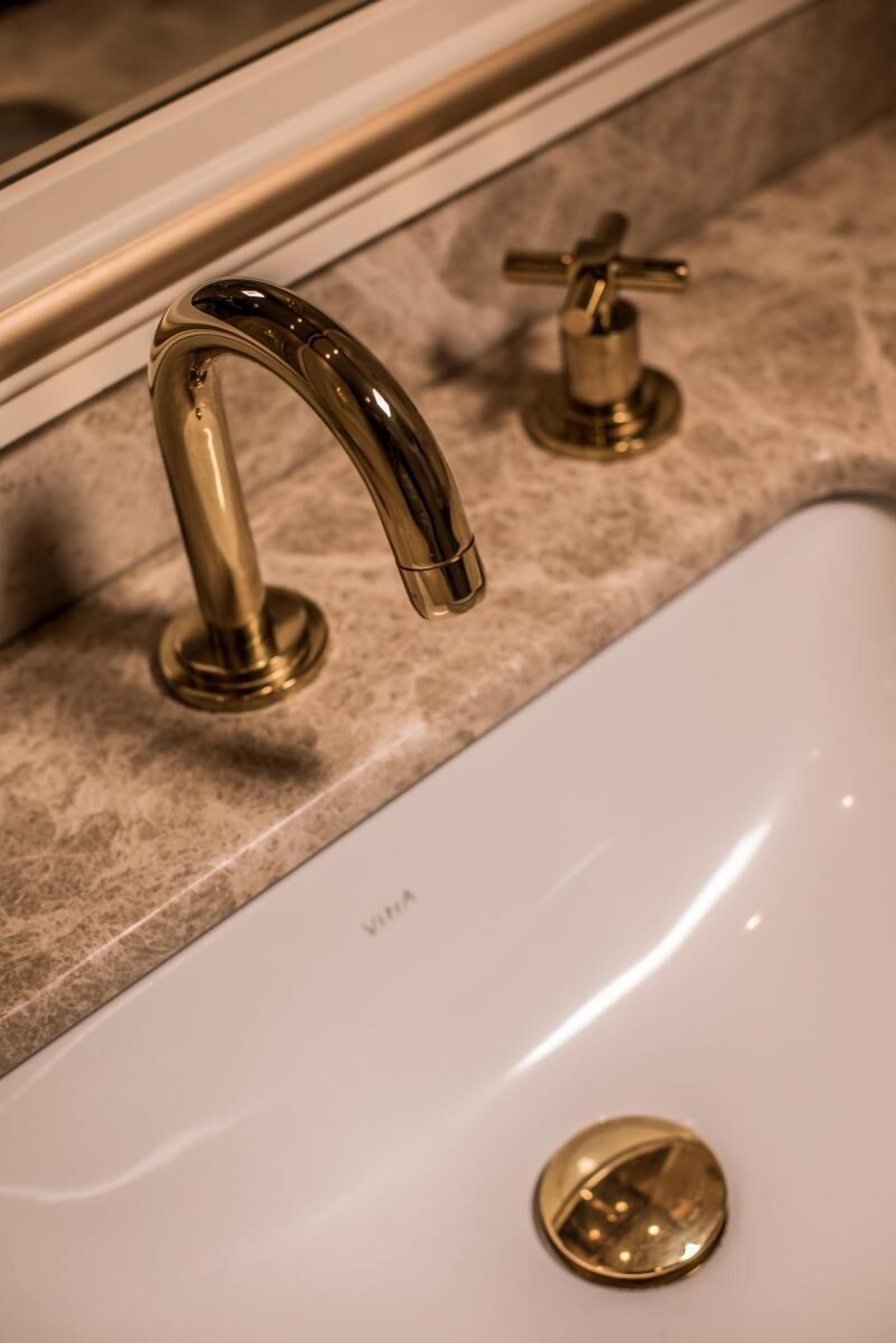 A bathroom sink with a gold faucet and a mirror above it.
