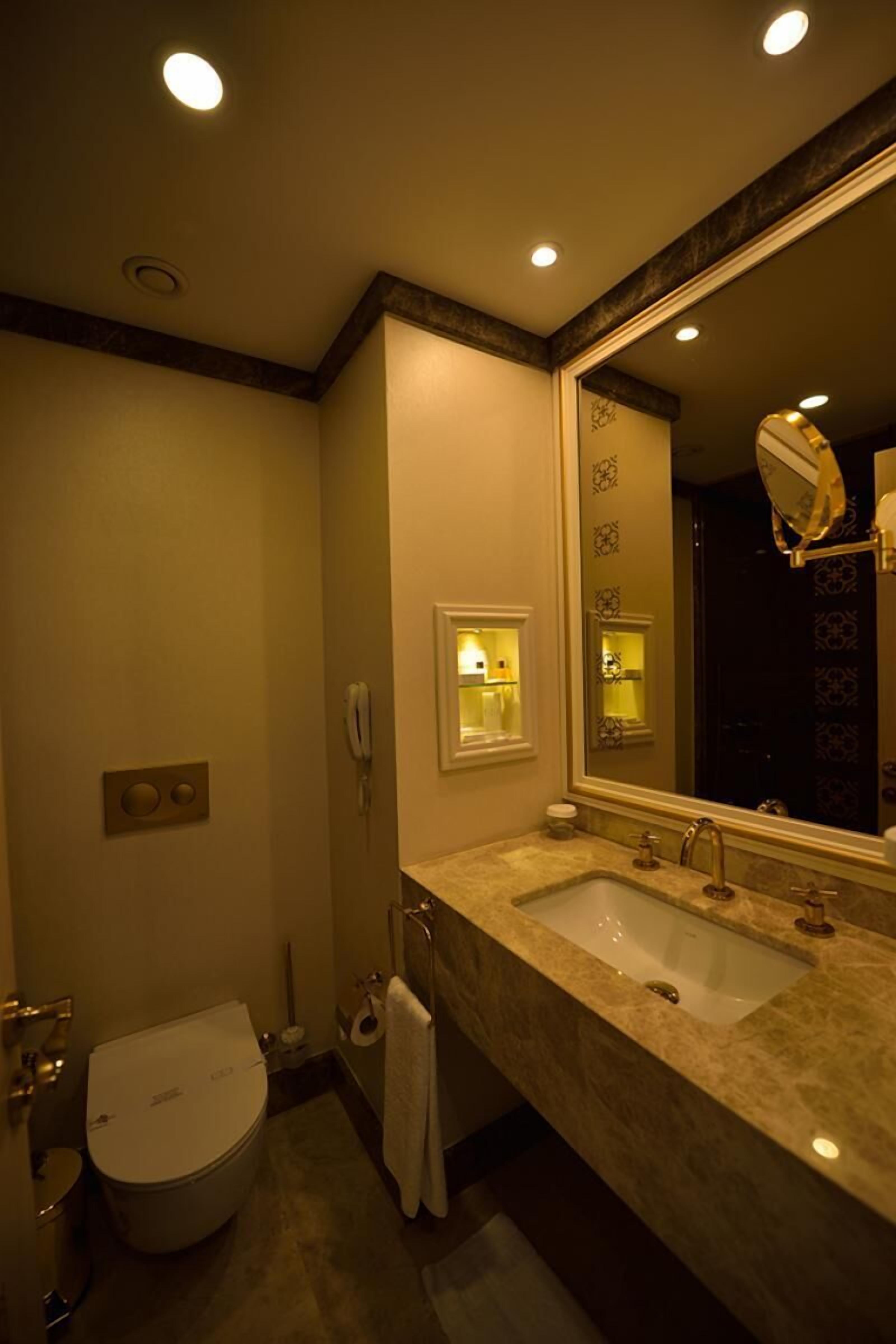 A bathroom with two sinks, a toilet, a mirror, and a towel rack.