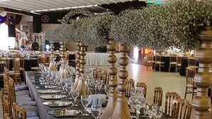 Een lange feesttafel gedekt met elegant servies en stoelen, waarschijnlijk in een hotel of evenementenlocatie.