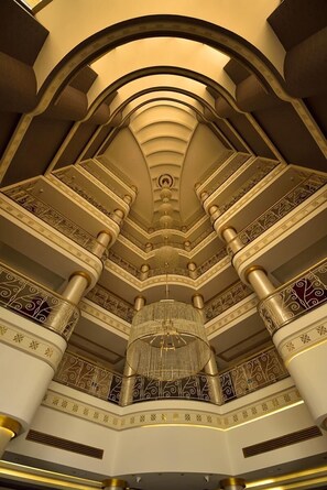Un interior majestuoso con una araña central, columnas ornamentadas y un diseño de techo escalonado.