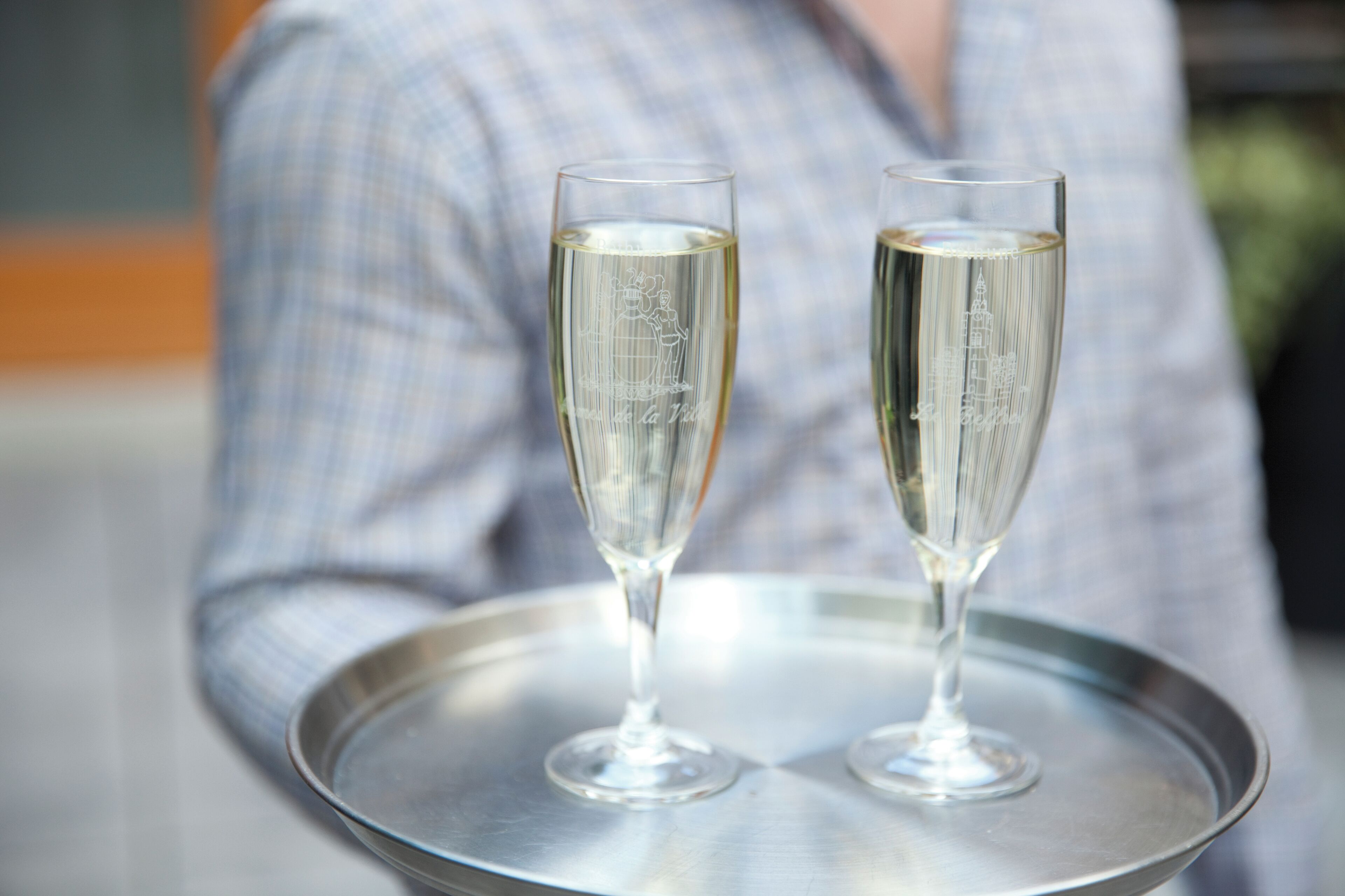 Two champagne flutes on a metallic tray.