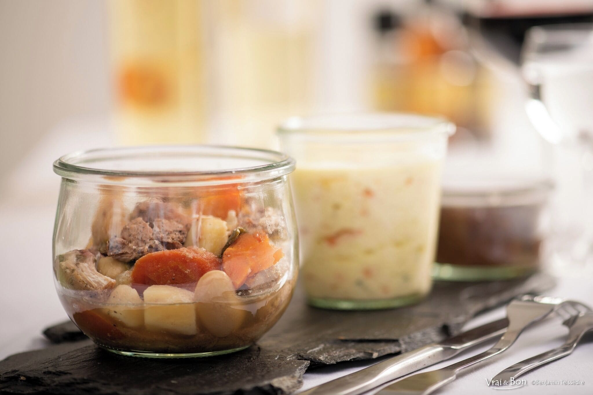Three glass jars containing different food items on a dark slate surface.