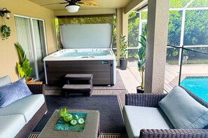 A spa area with a hot tub, seating, and a view of a swimming pool.
