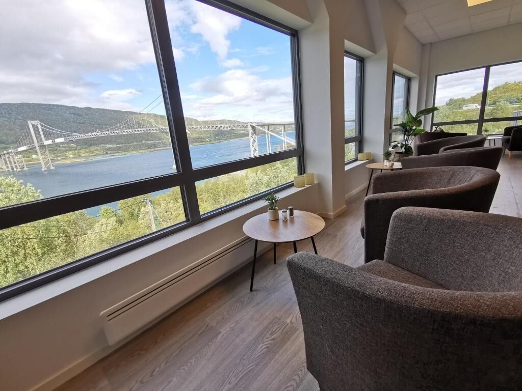 A room with large windows, a view of a bridge, and seating area.