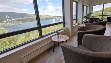 A room with large windows, a view of a bridge, and seating area.