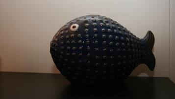 Un objeto azul oscuro en forma de pez, con un ojo blanco y múltiples pequeñas protuberancias sobre una superficie negra.