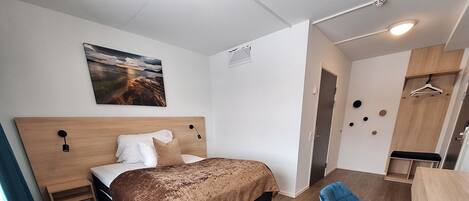 A modern bedroom with a bed, bedside tables, a desk, a chair, and a wardrobe.