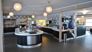 A modern kitchen area with a central island, overhead pendant lights, and a counter with a digital screen. - Tjeldsundbrua Hotel (Tjeldsund)