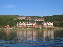 A waterfront property with multiple red buildings, a dock, and a large house in the background.