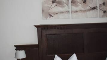 A hotel room with a bed, a nightstand with a lamp, and a wall-mounted artwork.