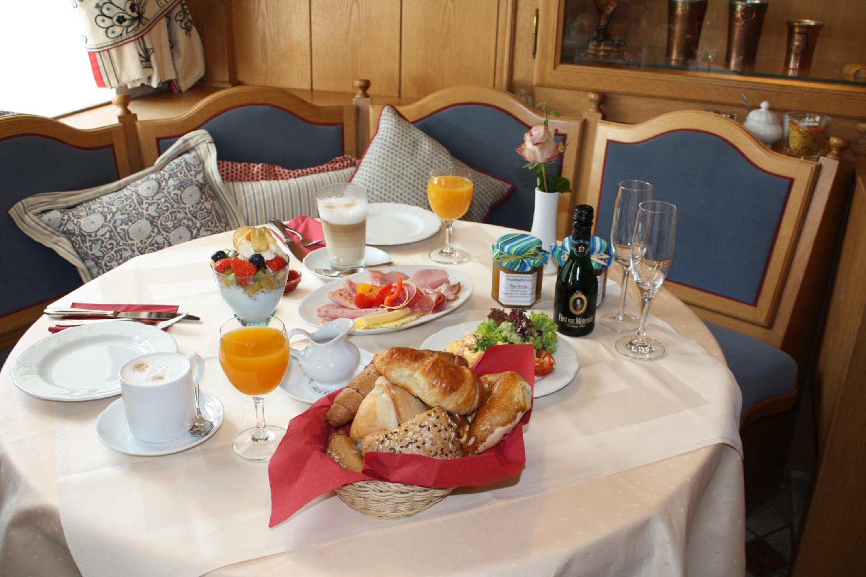 A breakfast table with plates of food, glasses of orange juice, and a bottle of champagne.