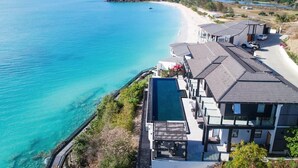 A coastal property with a private beach, a swimming pool, and a modern house with a flat roof. - Ocean Azul – Modern Infinity-Pool Villa Overlooking Darkwood Beach, Antigua and Barbuda (Ffryes beach)
