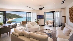 A modern living room with a large sofa, a dining table, and a view of the ocean. - Ocean Azul – Modern Infinity-Pool Villa Overlooking Darkwood Beach, Antigua and Barbuda (Ffryes beach)