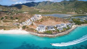 An aerial view of a coastal resort with multiple buildings, a sandy beach, and a clear blue sea. - Ocean Azul – Modern Infinity-Pool Villa Overlooking Darkwood Beach, Antigua and Barbuda (Ffryes beach)