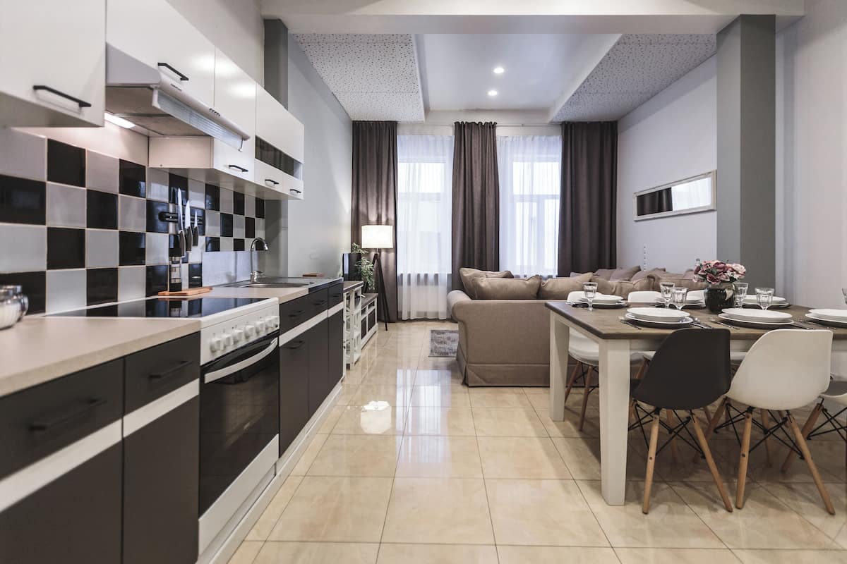A modern kitchen with black and white checkered backsplash, a dining area with a table set for four, and a living room with a sofa and a TV.