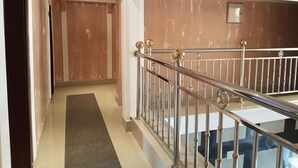 Un couloir avec une rambarde en métal, une porte en bois et un mur en marbre.