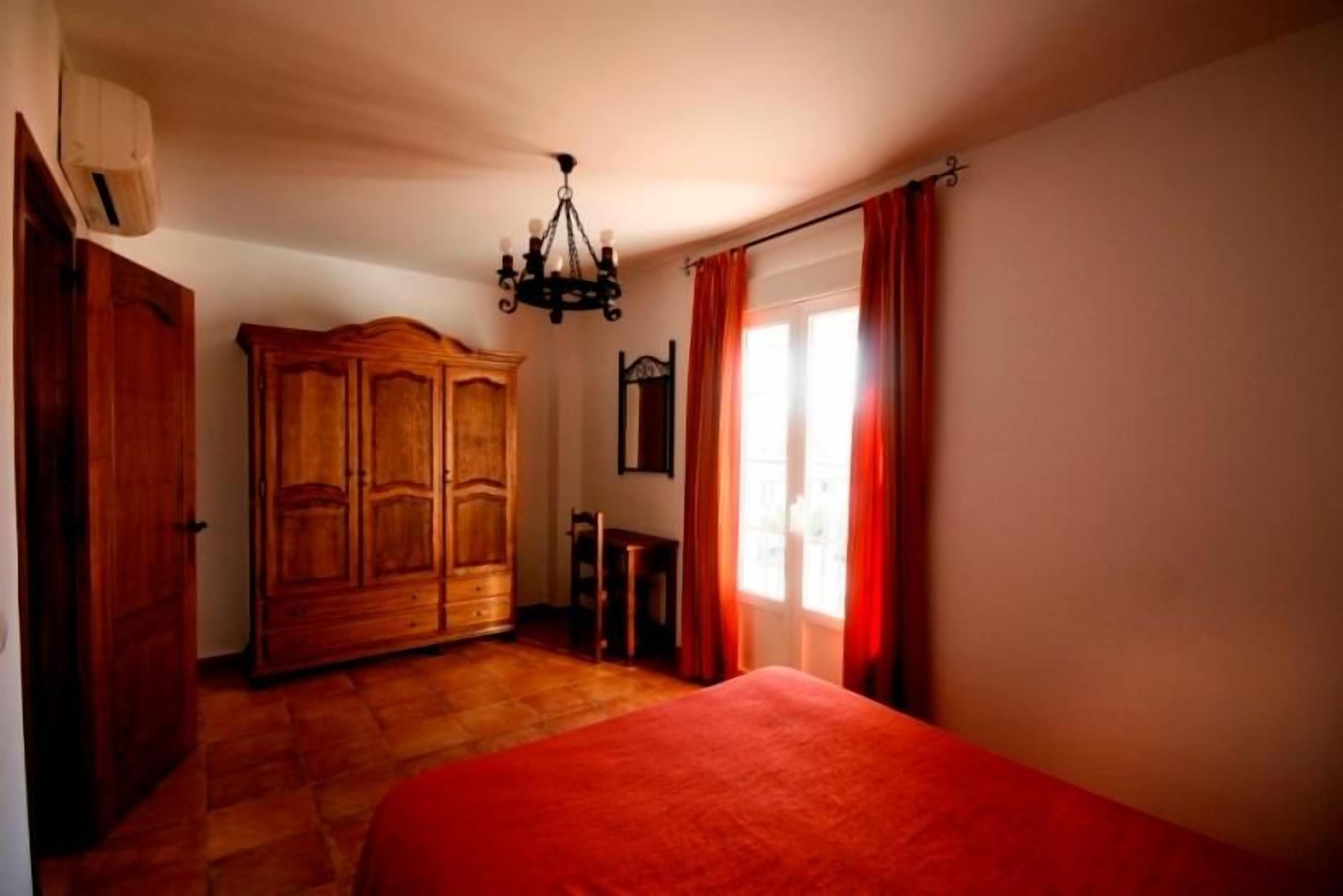 Ein Schlafzimmer mit einem großen Bett, einem Holzschrank und einer Kronleuchter.