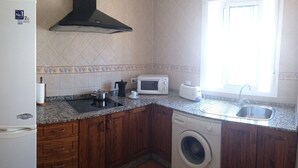 Uma cozinha compacta com geladeira, micro-ondas, torradeira, pia e máquina de lavar.