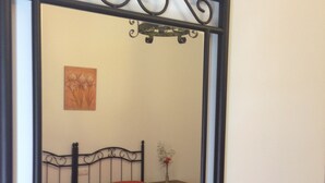 Um quarto com uma cama, uma mesa de cabeceira, um vaso com flores e um quadro na parede.