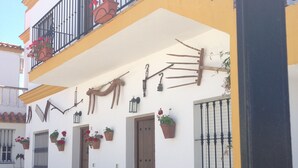 Um edifício com fachada amarela, várias varandas com grades pretas e diversos vasos com plantas.