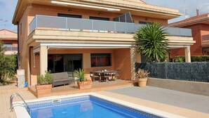 Une maison à deux étages dotée d’une piscine, d’un espace extérieur aménagé et d’un patio couvert.