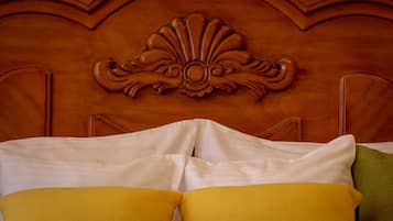 Uma cama com almofadas brancas e amarelas, cabeceira de madeira com detalhes entalhados e uma almofada verde.
