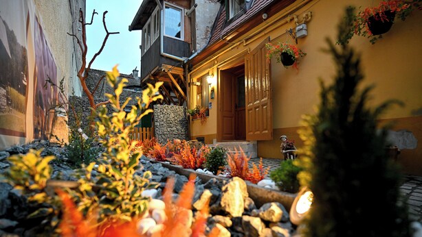 A courtyard with a stone pathway, a wooden bench, and a small fountain. - Hermannstadt House1 (Sibiu)