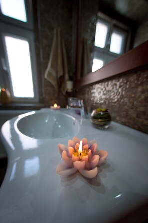 A bathroom with a white bathtub, a lit candle, and a window with curtains. - Hermannstadt House1 (Sibiu)