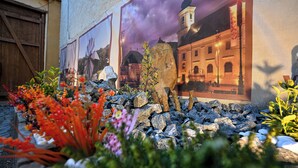 A garden with colorful flowers, a stone wall, and a mural of a building. - Hermannstadt House1 (Sibiu)