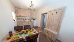A modern kitchen with wooden cabinets, a dining table set for four, and a chandelier. - Hermannstadt House1 (Sibiu)