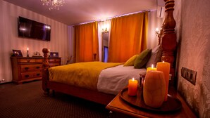 A neatly arranged bedroom with a bed, bedside table, dresser, and a flat-screen TV mounted on the wall. - Hermannstadt House1 (Sibiu)