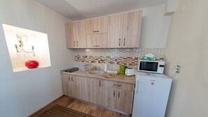 A compact kitchen with light wood cabinets, a white refrigerator, a microwave, and a sink. - Hermannstadt House1 (Sibiu)
