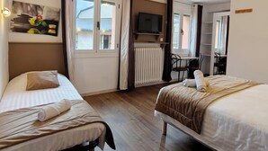 Een hotelkamer met twee bedden, een televisie, een bureau en een stoel.