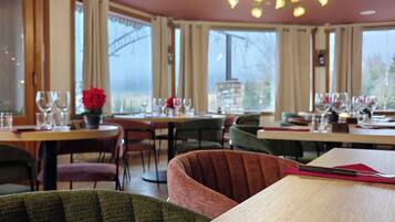 Un restaurant avec des tables rondes, des chaises et un lustre.