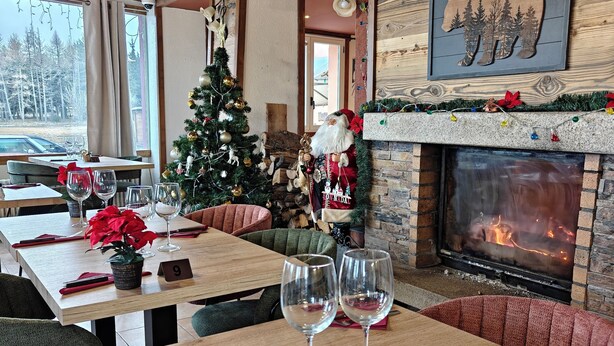Een gezellig restaurant met een open haard, kerstversiering en uitzicht op het buitengebeuren.