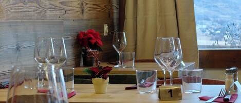 A dining table set with wine glasses, a water glass, and a small potted plant.