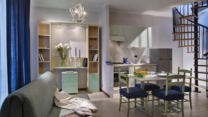 Una sala de estar moderna con un sofá, una mesa de comedor, sillas y una escalera.